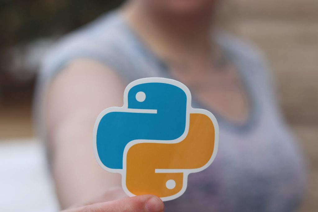 The Entrepreneur’s Guide to Turning Ideas Into Profitable Person holding Python logo sticker with blurred background, highlighting programming focus.